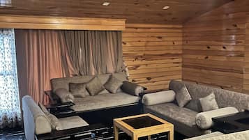 Una sala de estar acogedora con un sofá modular, una pequeña mesa de centro de madera y un mueble bajo para la televisión negro.