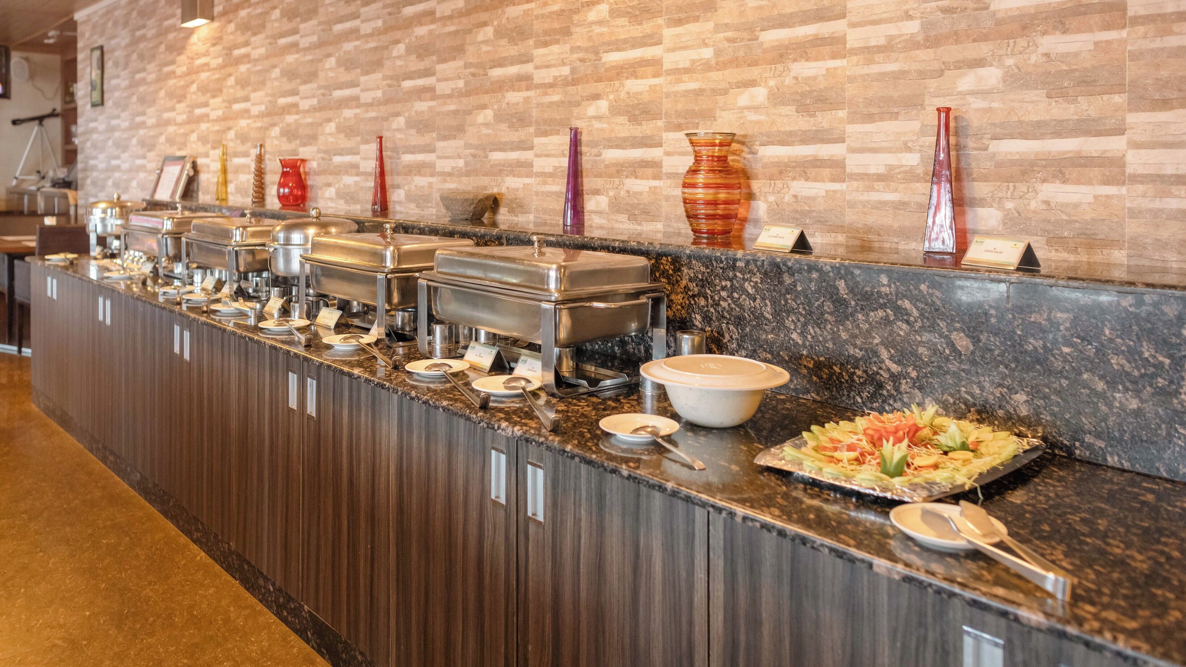 Ein Buffet mit mehreren Speisestationen, einer Marmorplatte und einer Ziegelwand im Hintergrund.