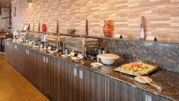 Ein Buffet mit mehreren Speisestationen, einer Marmorplatte und einer Ziegelwand im Hintergrund.