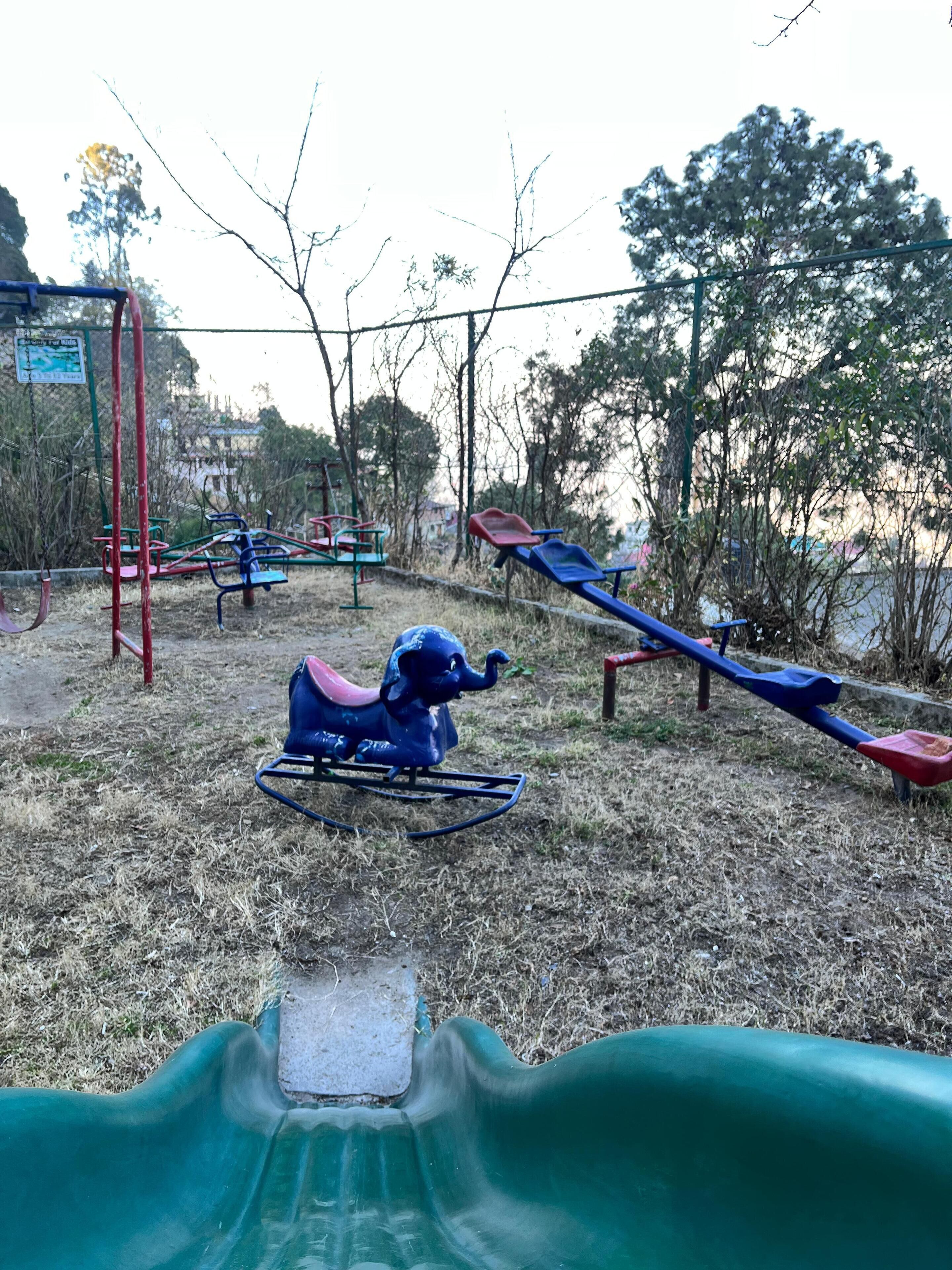 A playground with various play equipment including swings, slides, and a seesaw.