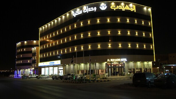 Un hotel con fachada curva, varios pisos y señalización iluminada.