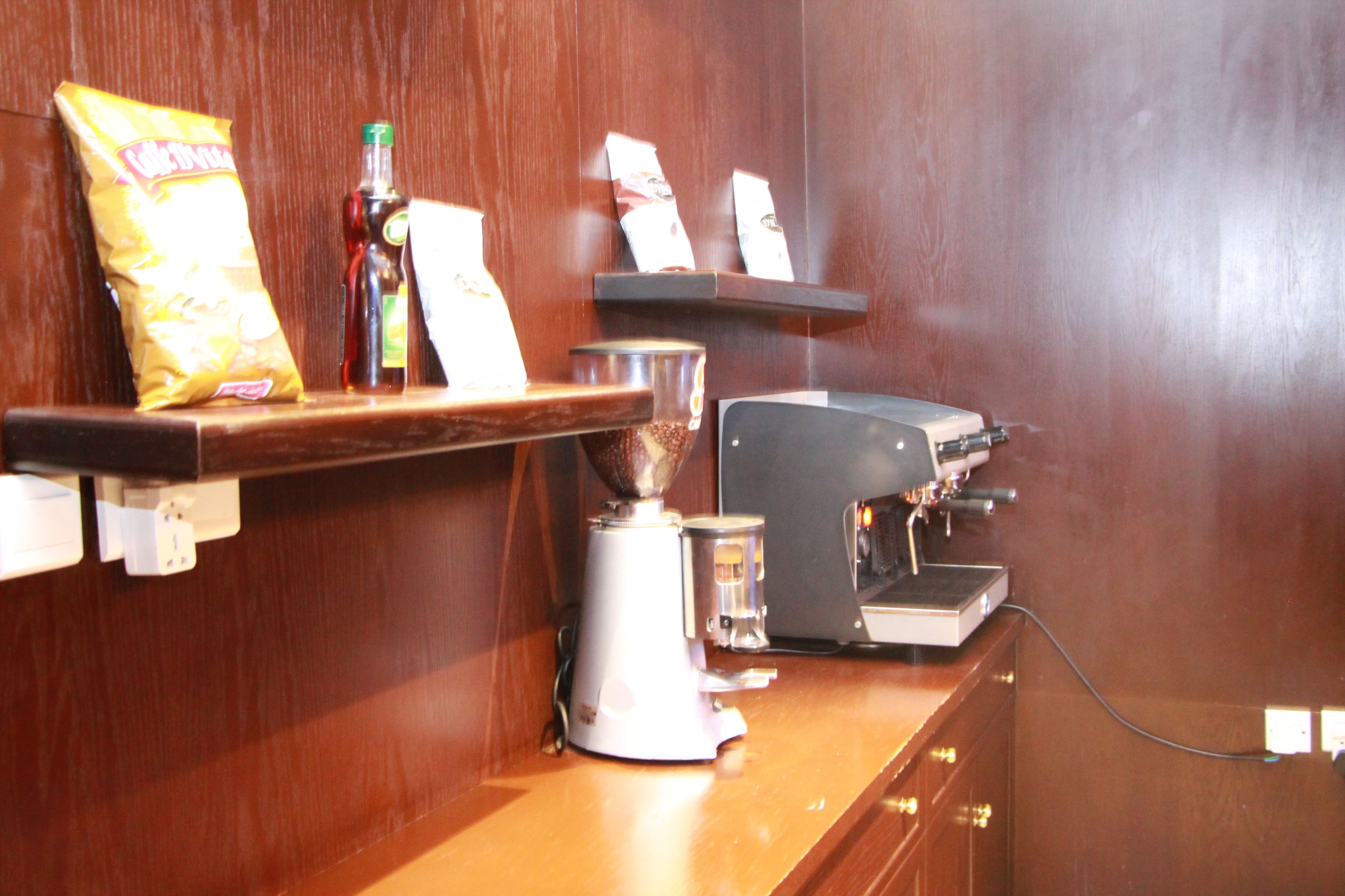 Une machine à café, un paquet de chips et un moulin à café sur un comptoir en bois.
