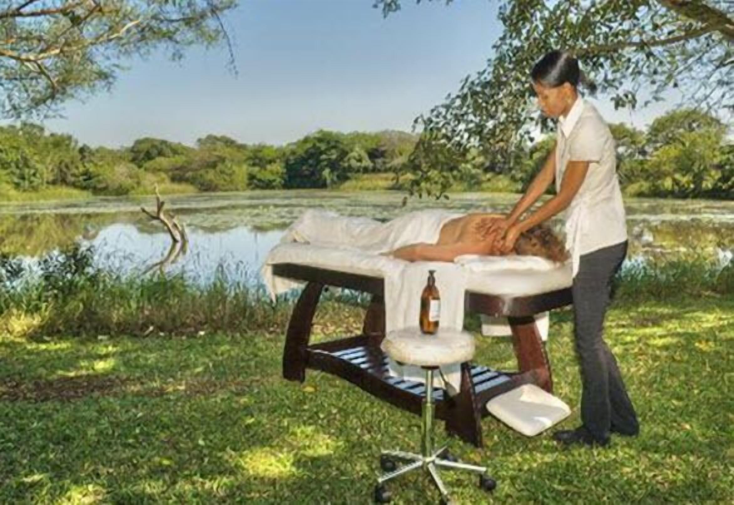 A massage table set up outdoors with a person attending to a client.