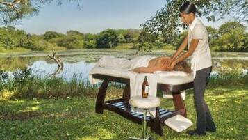 A massage table set up outdoors with a person attending to a client.