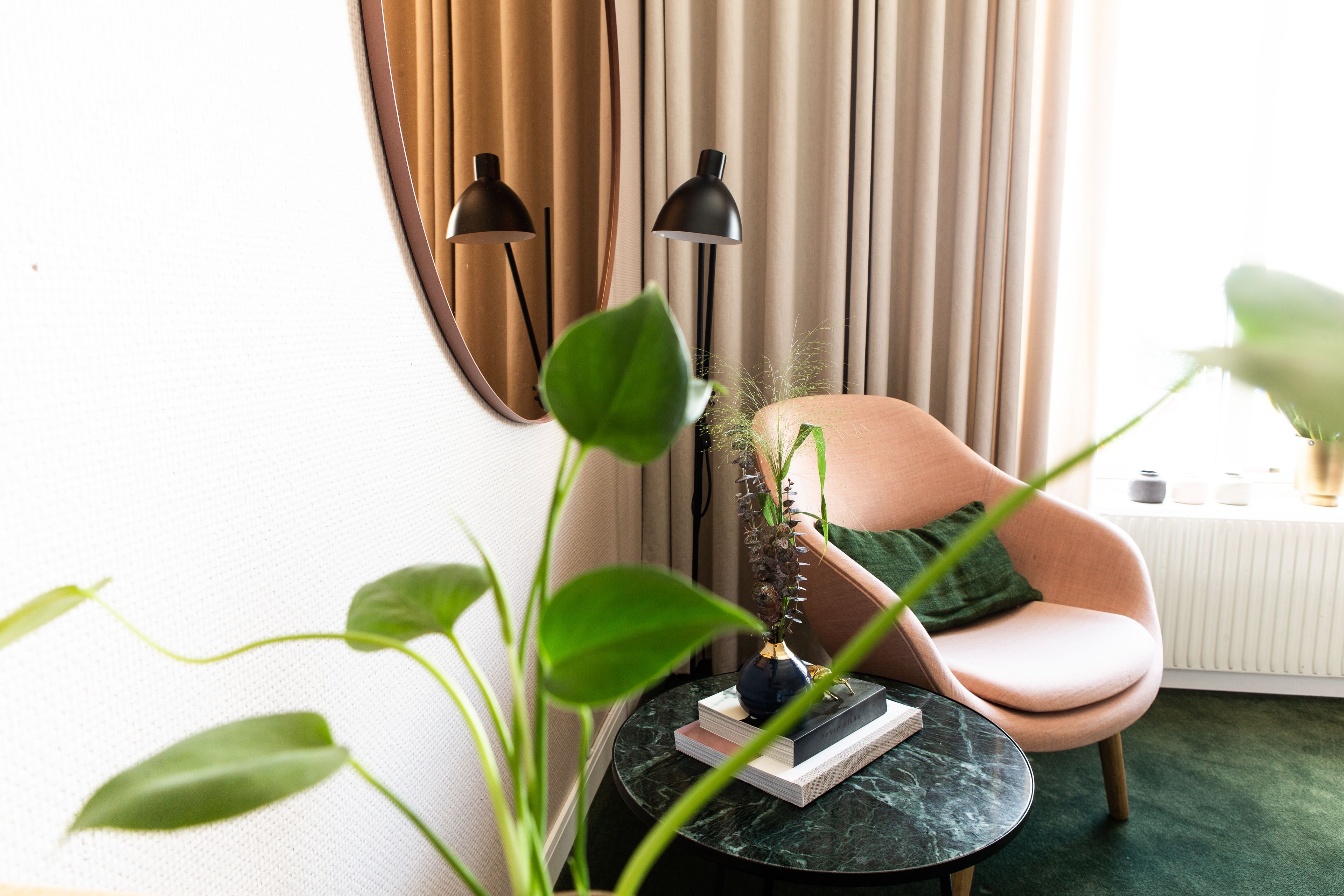 A cozy room with a round table, a chair, a floor lamp, and a potted plant.