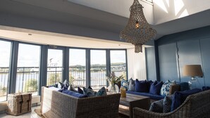 A modern living room with large windows, wicker furniture, and a hanging light fixture. - Hotell Bogesund (Ulricehamn)