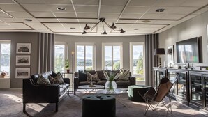 A spacious living room with a large window, a sofa set, a coffee table, and a television. - Hotell Bogesund (Ulricehamn)