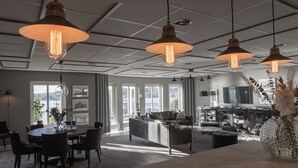 A modern living room with a dining area, large windows, and hanging pendant lights. - Hotell Bogesund (Ulricehamn)