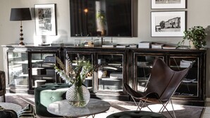 A modern living room with a large flat-screen TV, a glass coffee table, and comfortable seating. - Hotell Bogesund (Ulricehamn)