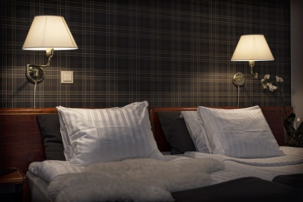 Habitación de hotel con una cama, dos lámparas de pared y un arreglo floral.
