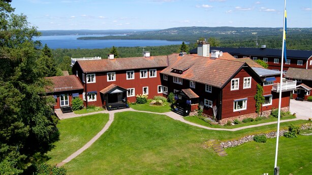 A large red building with multiple windows and a well-maintained lawn. - Villa Långbers (Tallberg)