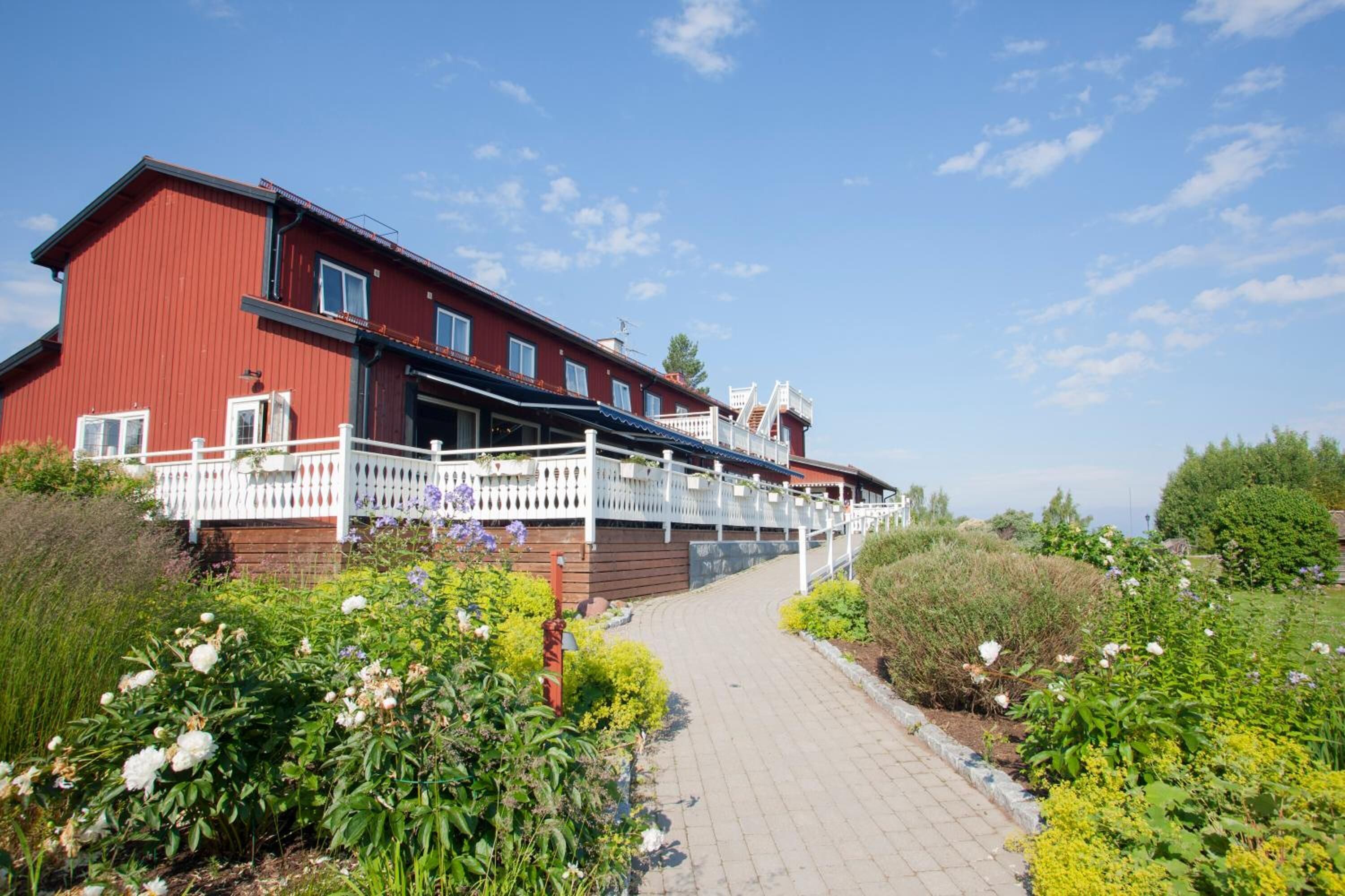 A red building with a white fence and a paved pathway leading to it.