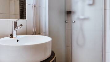 Un baño con lavamanos blanco, un espejo y una puerta de ducha.
