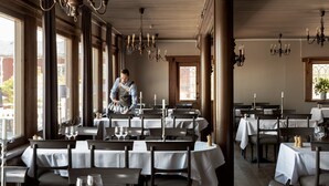 A restaurant with multiple tables, each set with white tablecloths and candles. - Villa Långbers (Tallberg)