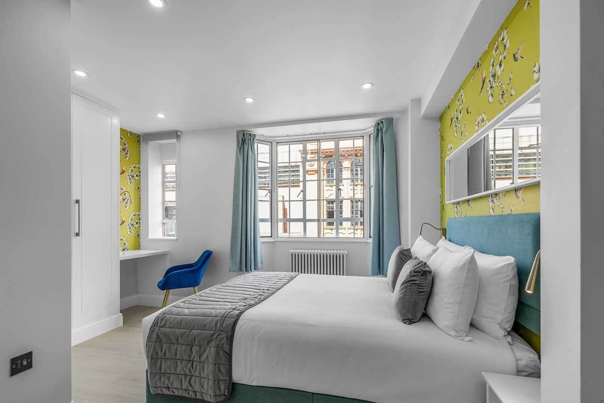 Une chambre à coucher moderne avec un lit, une chaise, une fenêtre et un radiateur.