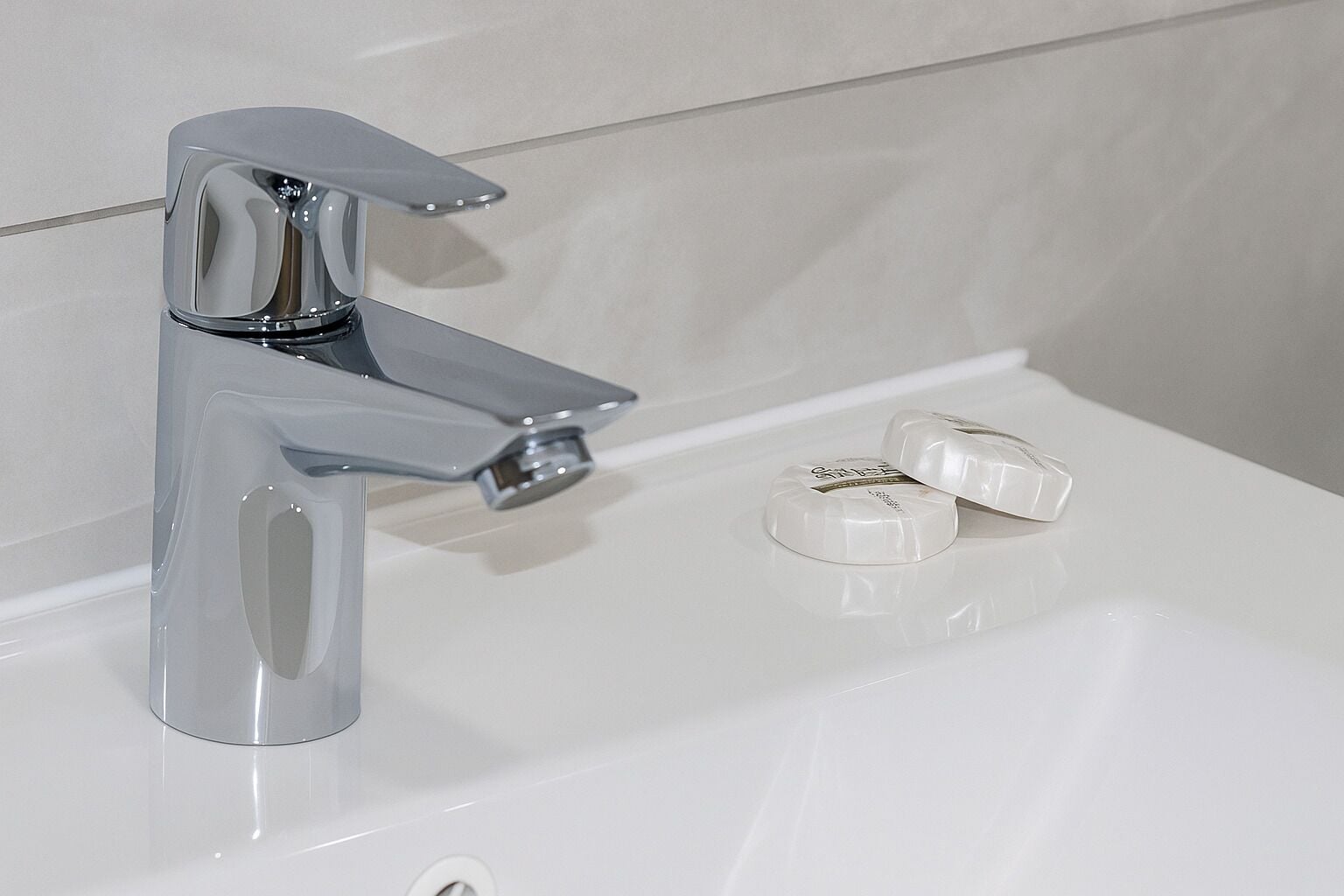 Een moderne badkamer met een chromen kraan en een witte wastafel.