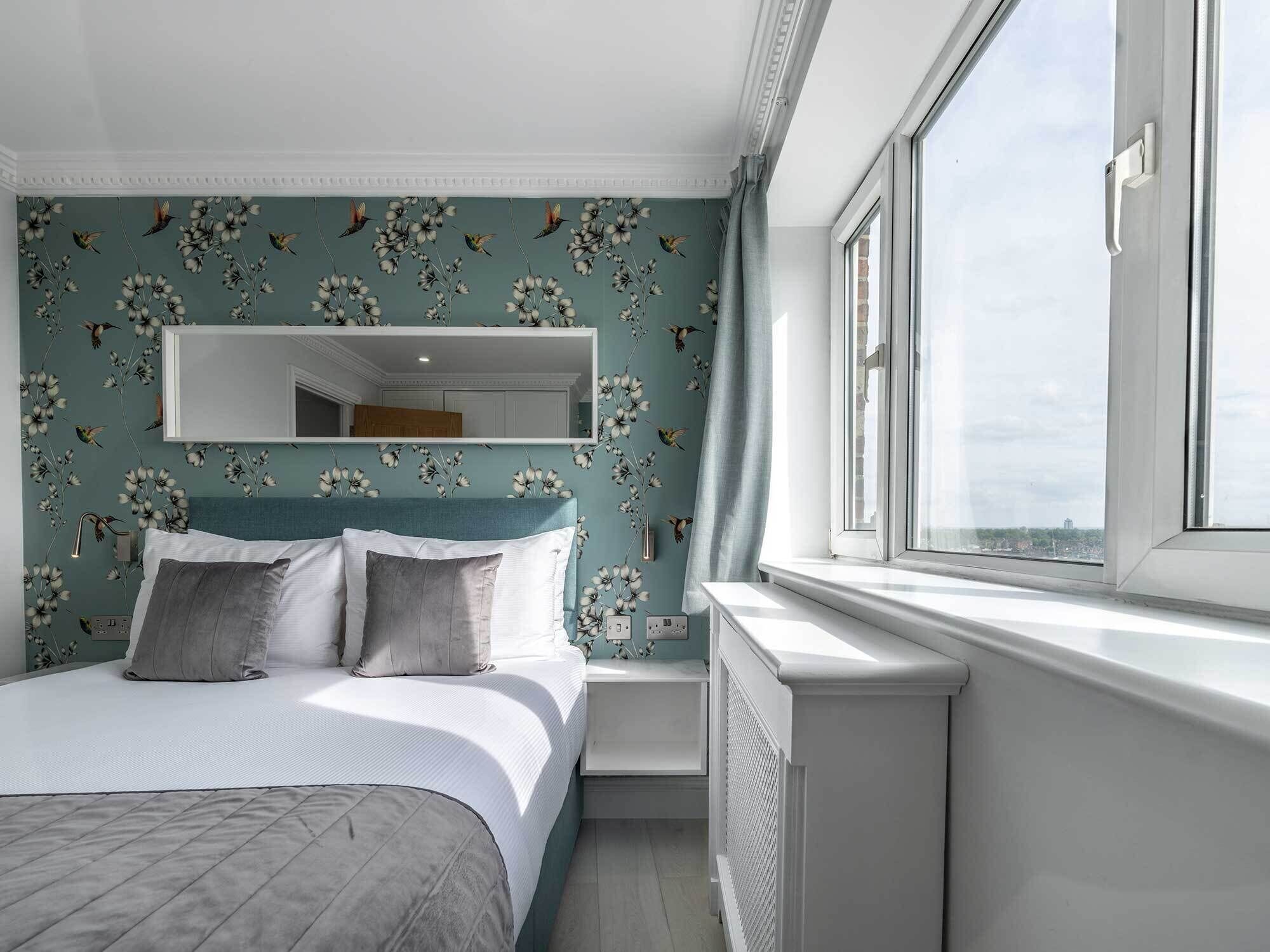 Une chambre à coucher avec un lit, un grand miroir et une fenêtre donnant sur un beau paysage.