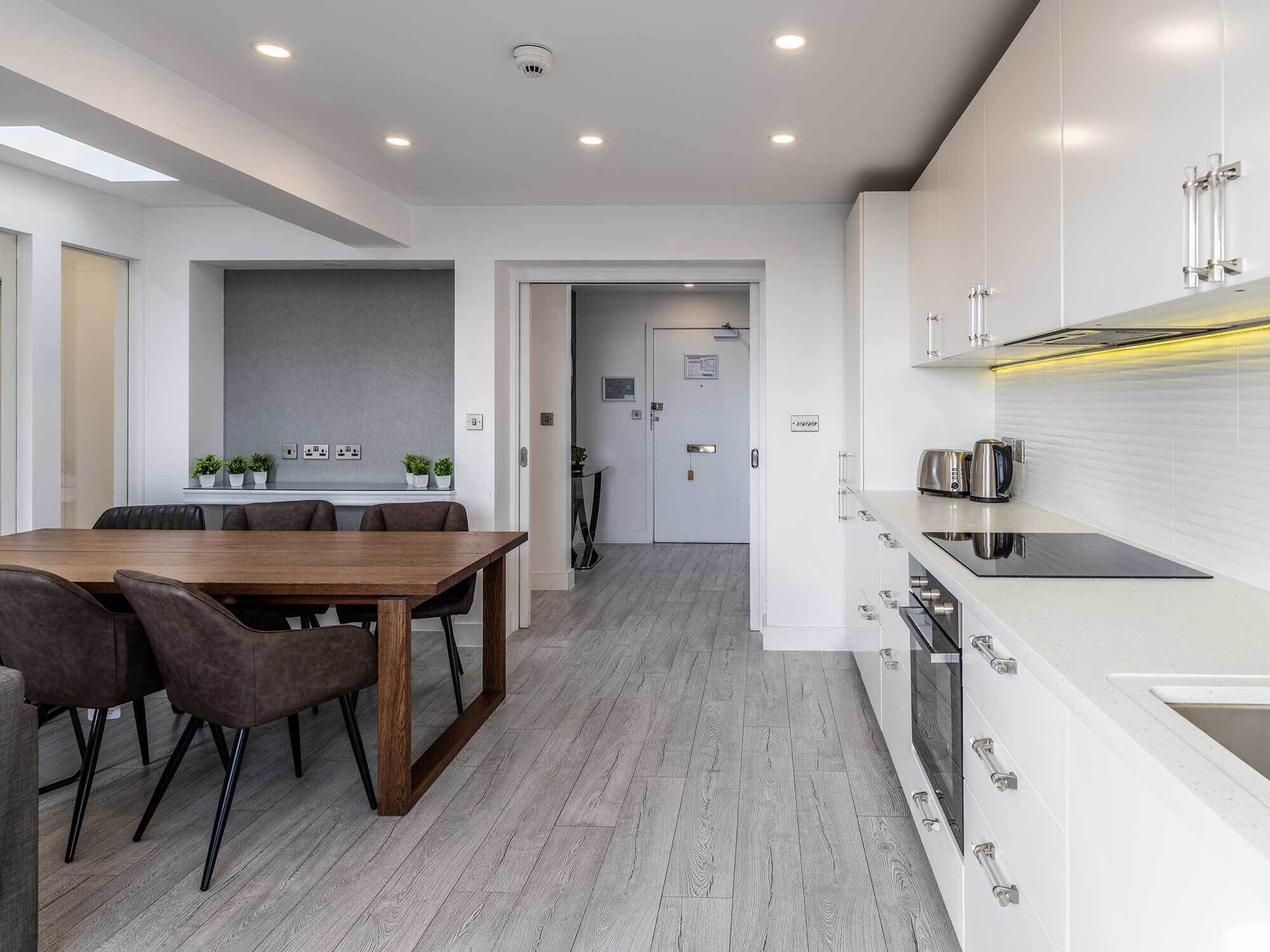 A modern kitchen with white cabinets, a black countertop, and a built-in stove.