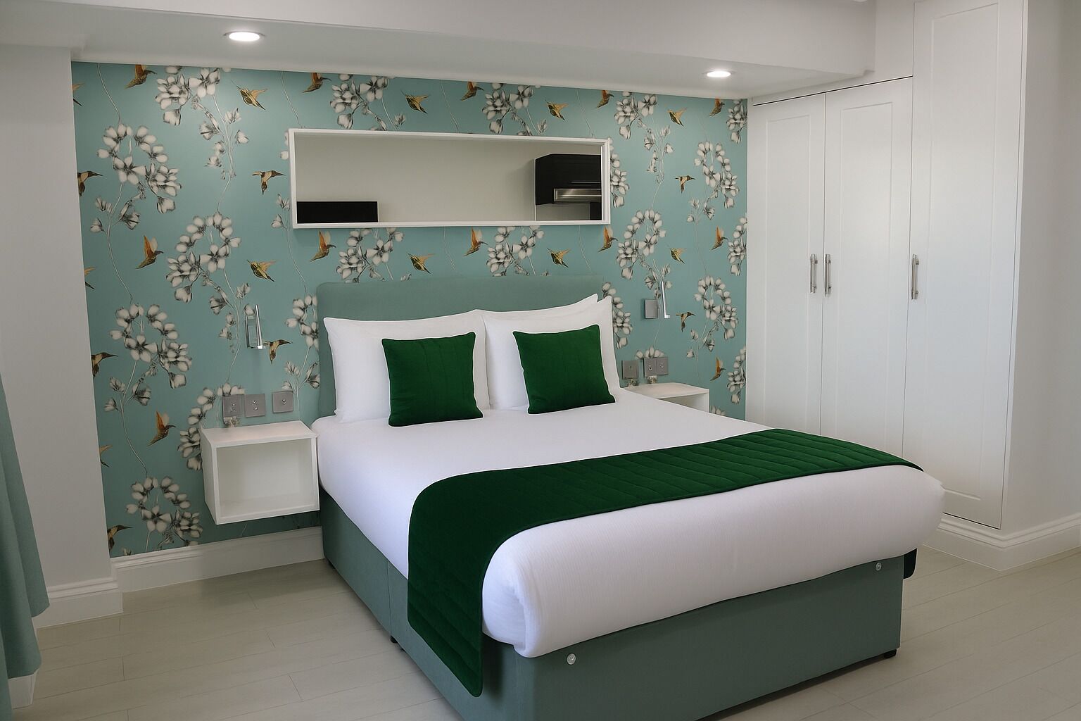 A bedroom with a bed, green pillows, a nightstand, a dresser, and a mirror.