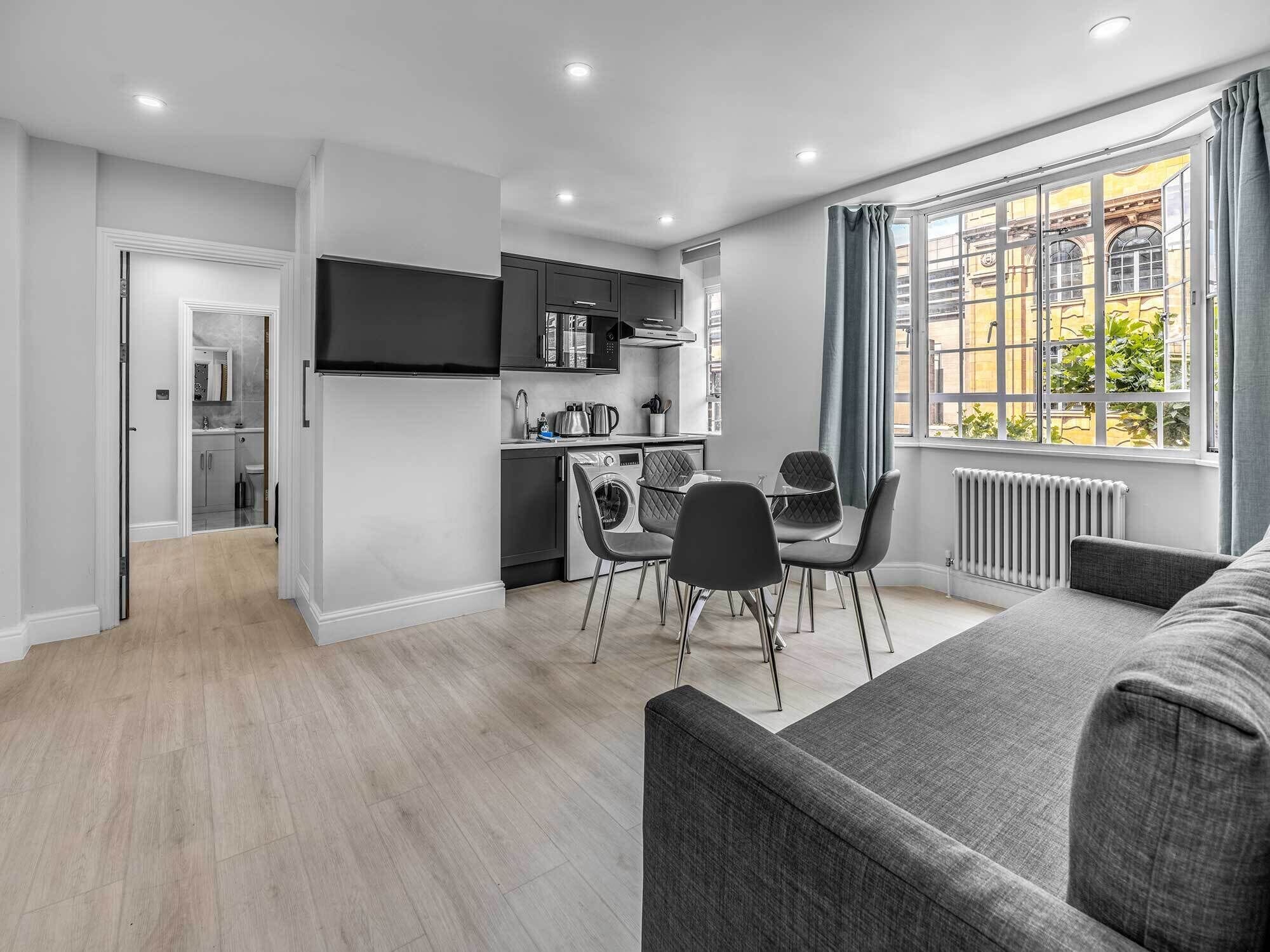 A modern apartment with a kitchen, dining area, and a living room with a large window.