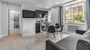A modern apartment with a kitchen, dining area, and a living room with a large window.