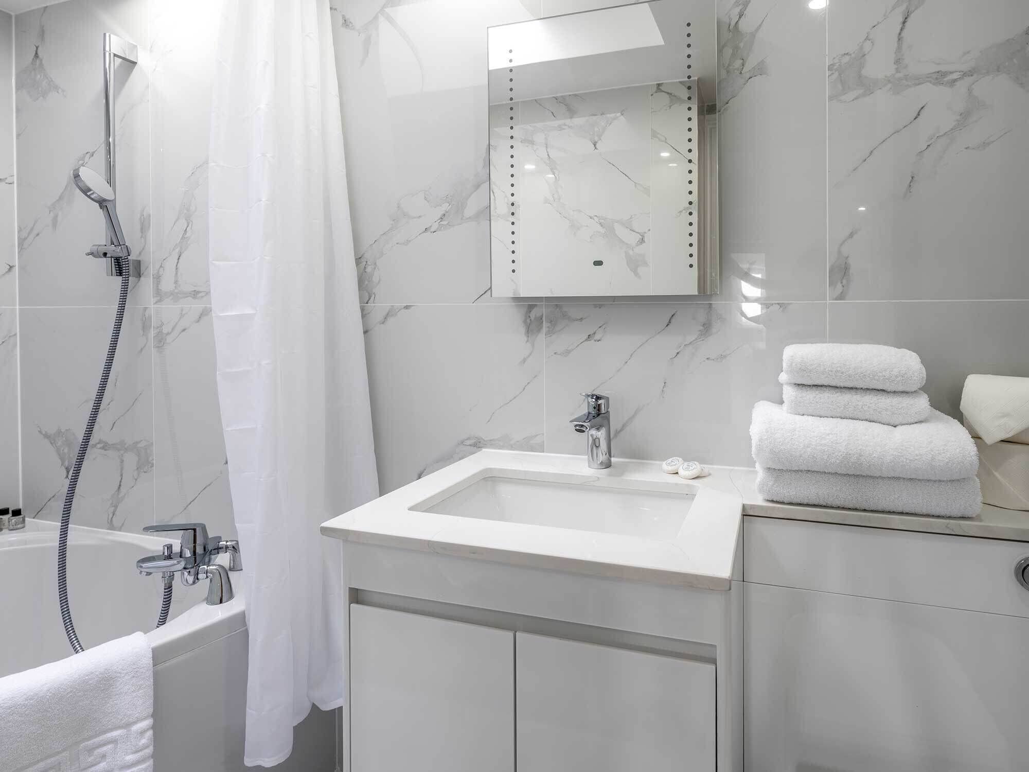A modern bathroom with a bathtub, a shower, a sink, and a mirror.