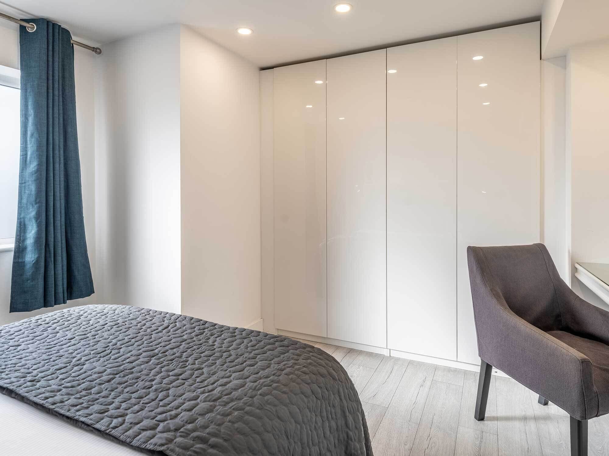 A modern bedroom with a bed, a chair, and a wardrobe.
