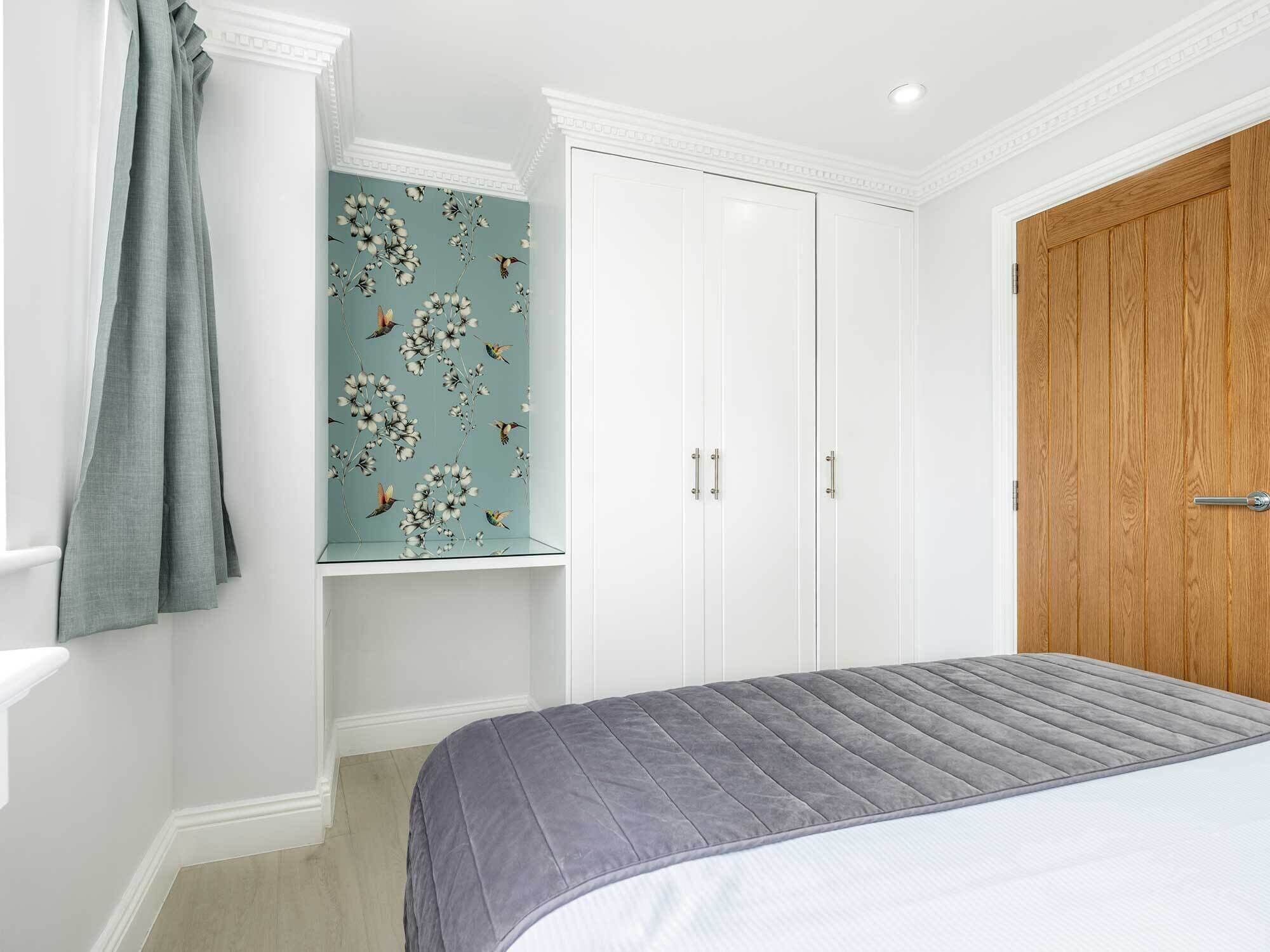 Een slaapkamer met een bed, een kledingkast en een raam met gordijnen.
