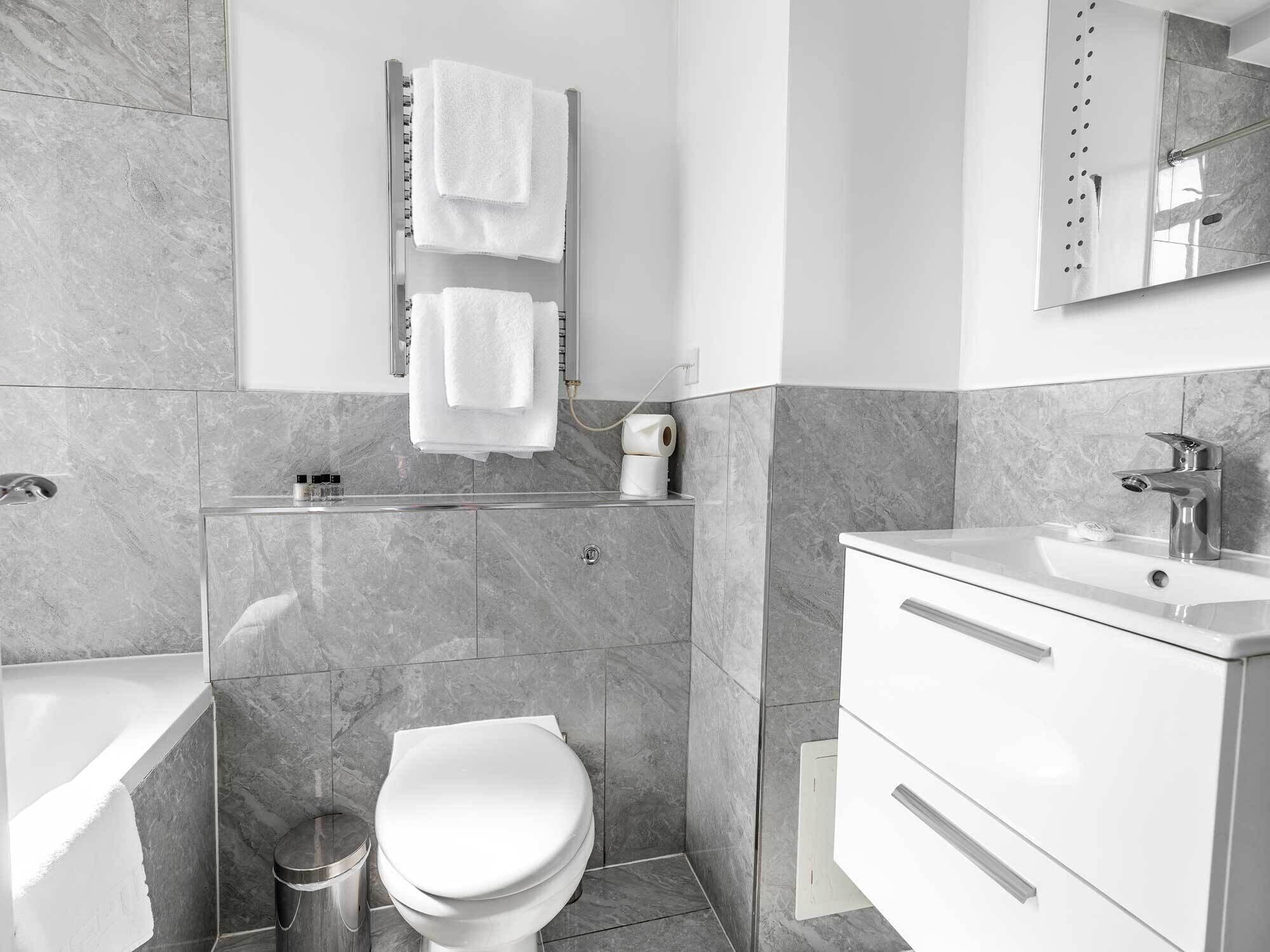 A modern bathroom with a bathtub, toilet, and vanity.