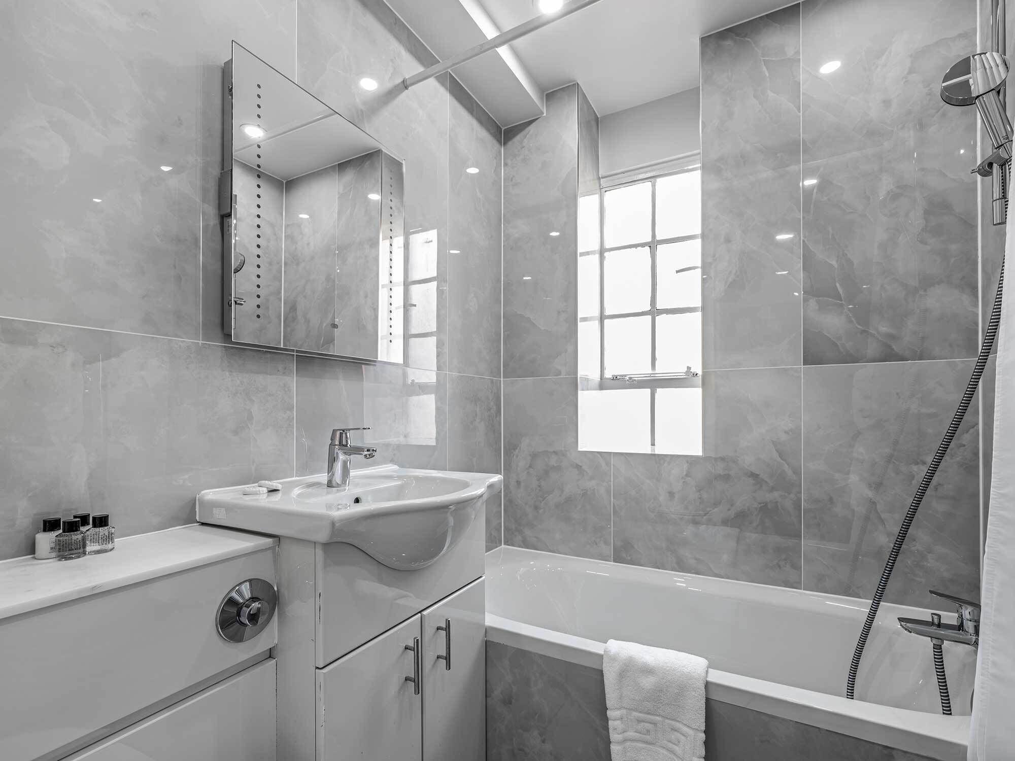 A modern bathroom with a sink, mirror, and shower.