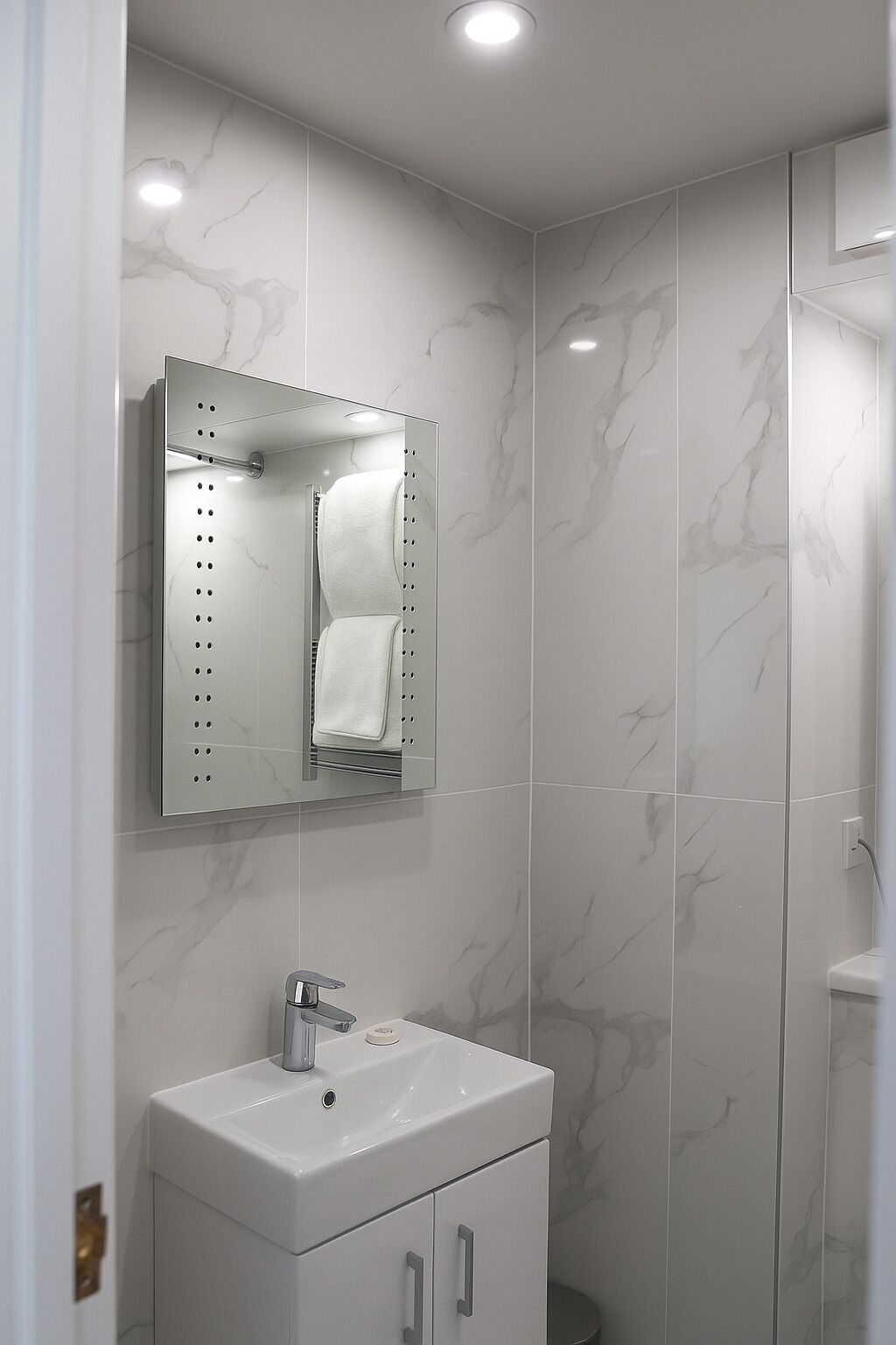 A bathroom with a marble wall, a sink with a mirror, and a shower area.