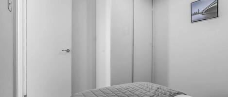 A minimalist bedroom with a bed, a door, and a framed picture on the wall.