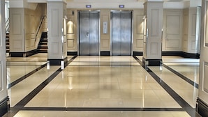 A hotel lobby with a polished floor, double doors, and a staircase. - Chelsea Cloisters Serviced Apartments (London)