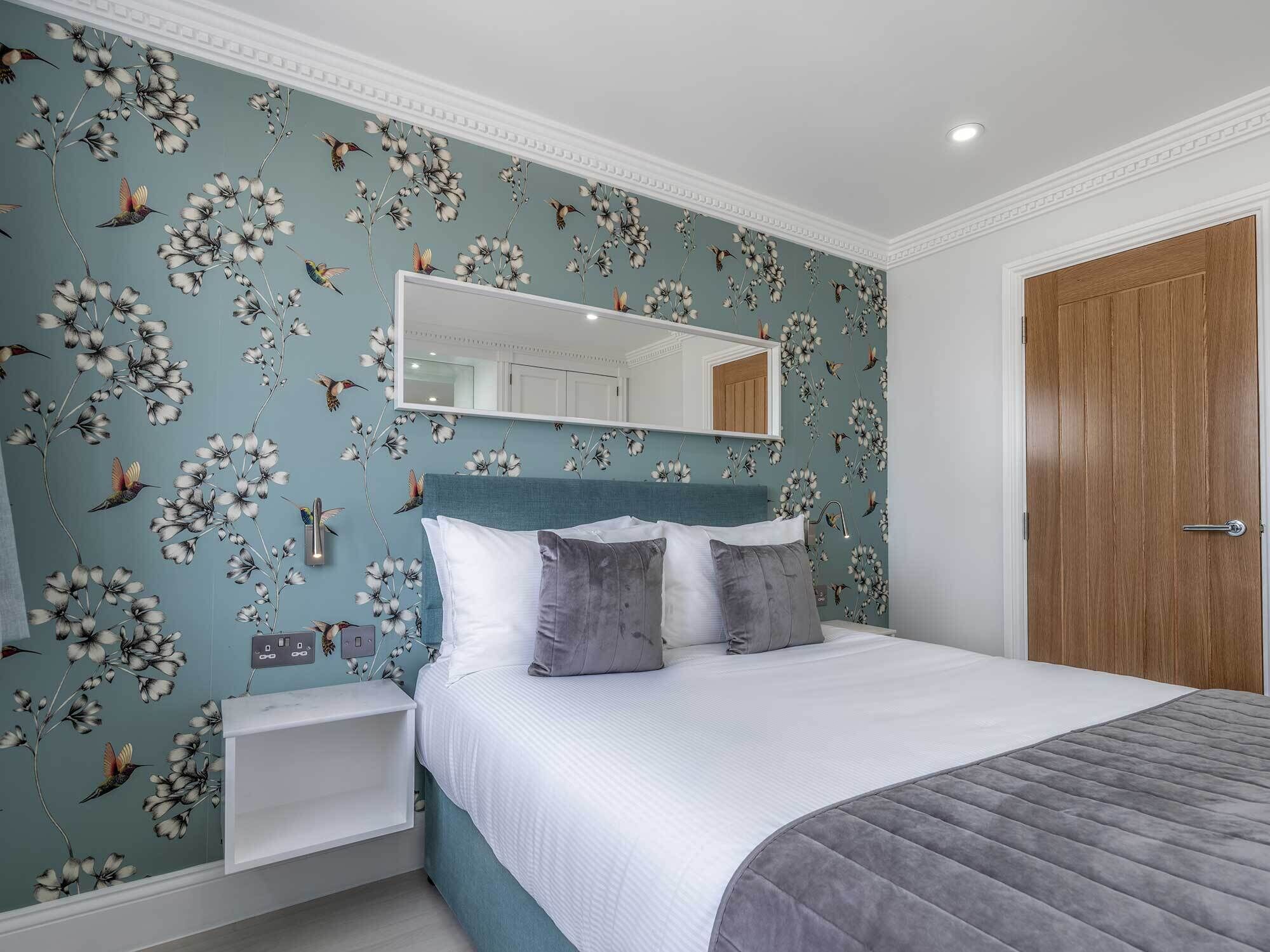Une chambre à coucher avec un lit, une table de chevet, un miroir et une porte en bois.