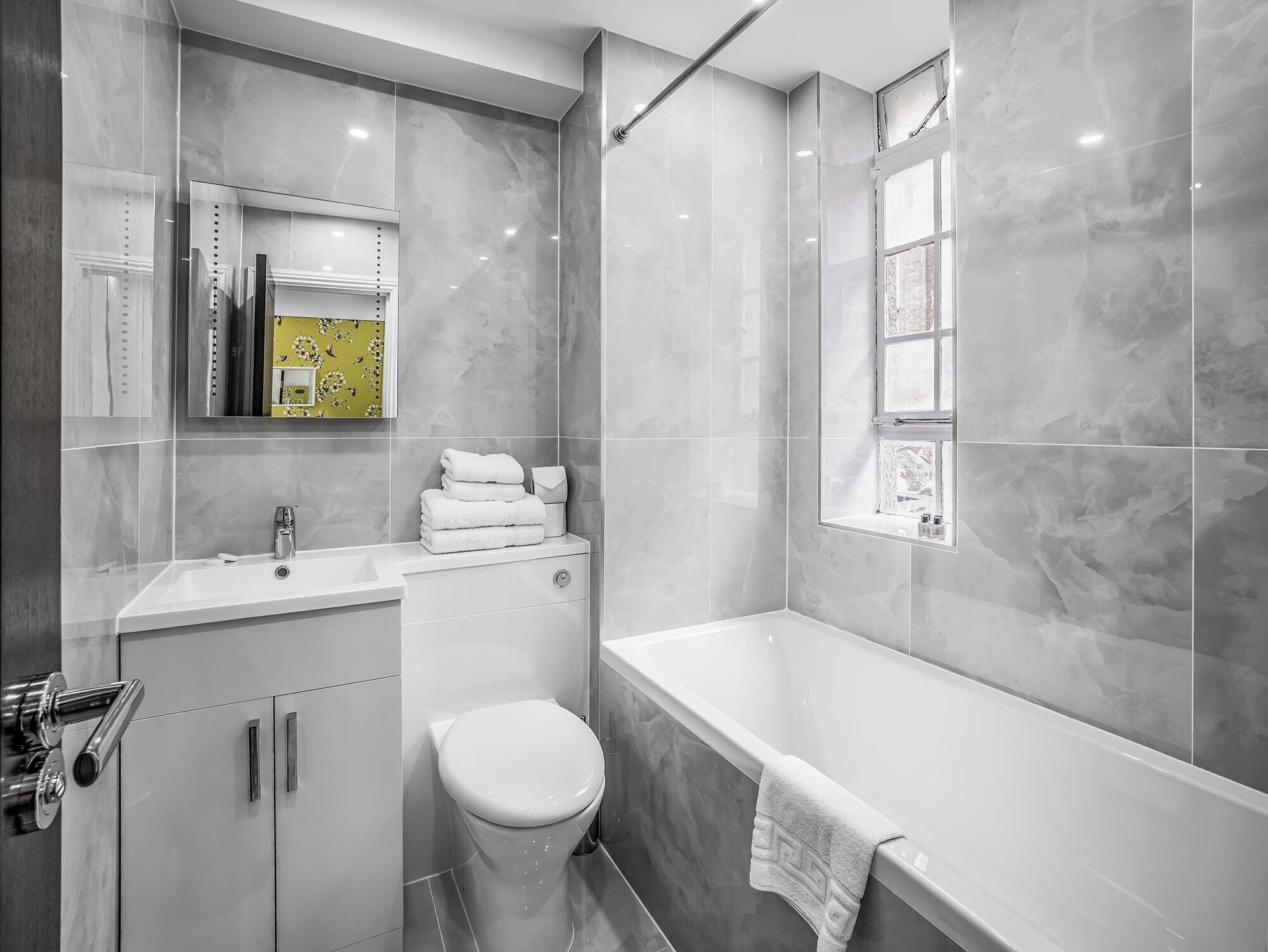 Ein modernes Badezimmer mit einer großen Badewanne, einer Toilette und einem Waschtisch mit Spiegel.