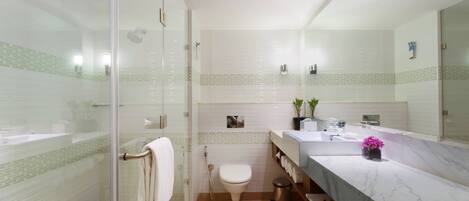 A modern bathroom with a glass shower enclosure, a toilet, a sink with a marble countertop, and a mirror.
