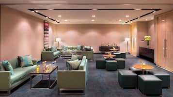 A modern lounge area with sofas, armchairs, and a bar area.