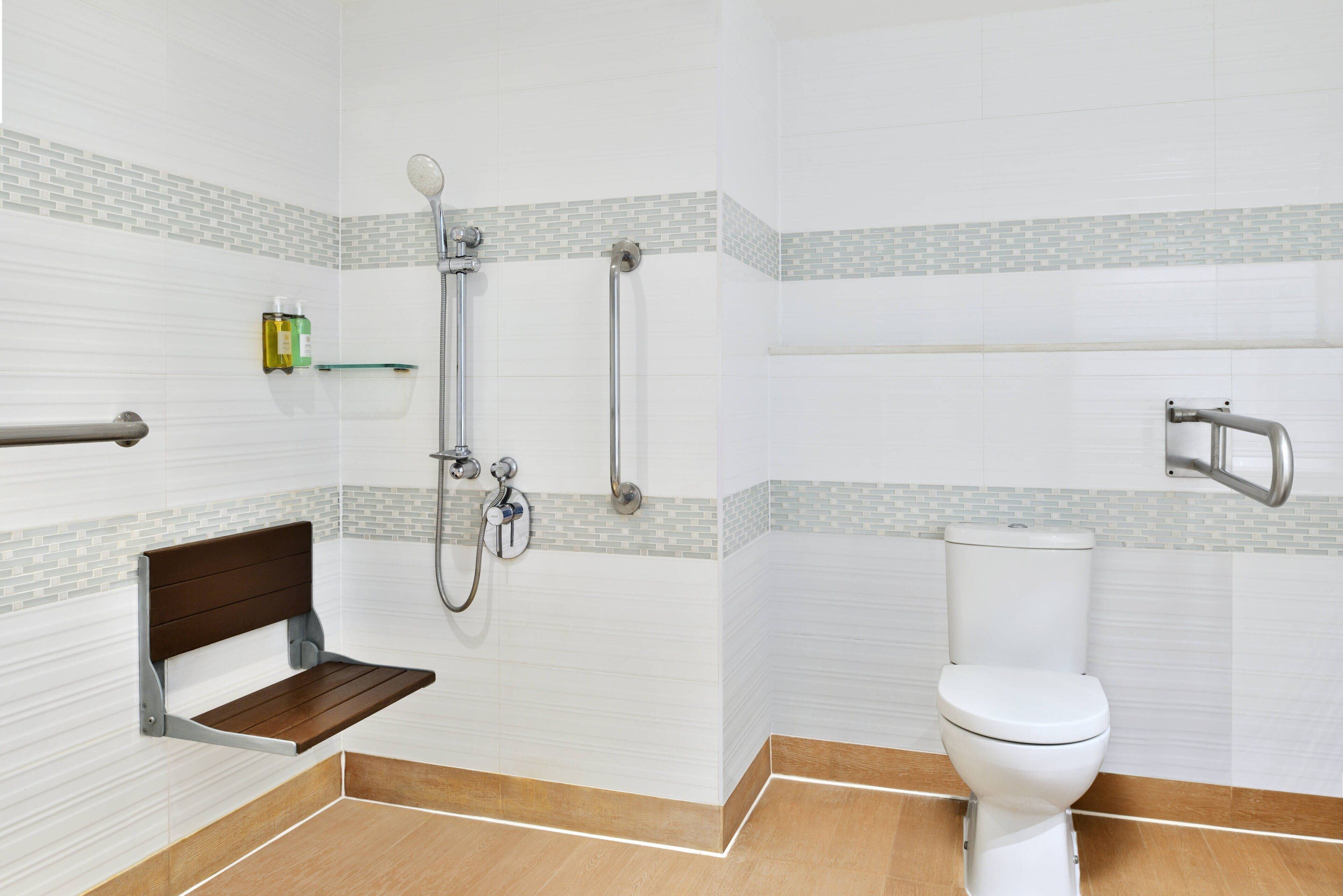 Un baño con ducha, inodoro y un banco.
