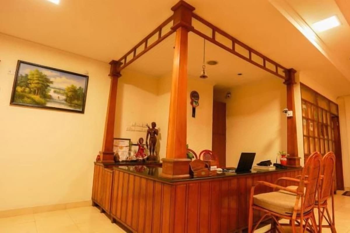 Un área de recepción con un mostrador de madera, sillas y un espejo grande.