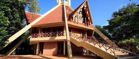 A building with a red roof, a balcony, and a staircase leading to the entrance.