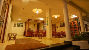 A spacious lobby with a central seating area, a reception desk, and a staircase leading to upper floors. - Sanctum Spring (Varkala)