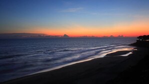 A beach at sunset with waves lapping onto the shore. - Sanctum Spring (Varkala)