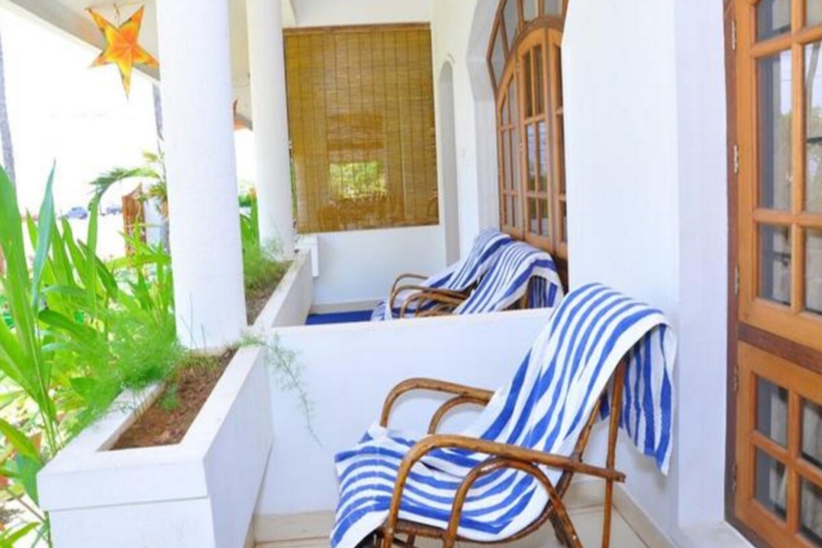 A balcony with two wicker chairs, a star decoration, and a window with a wooden frame.