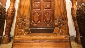 Een grote, versierde houten deur met ingewikkelde houtsnijwerken en een plaquette erboven.