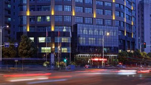 Un hotel moderno con fachada curva, varios pisos y ventanas iluminadas.