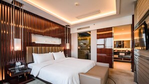 Una habitación de hotel moderna con una cama grande, un área de descanso, una tocador con espejo y un televisor.