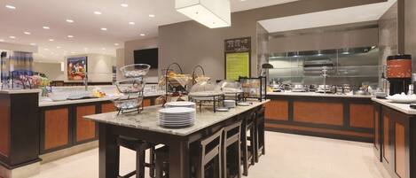 A modern hotel kitchen with a central island, buffet setup, and a professional cooking area.
