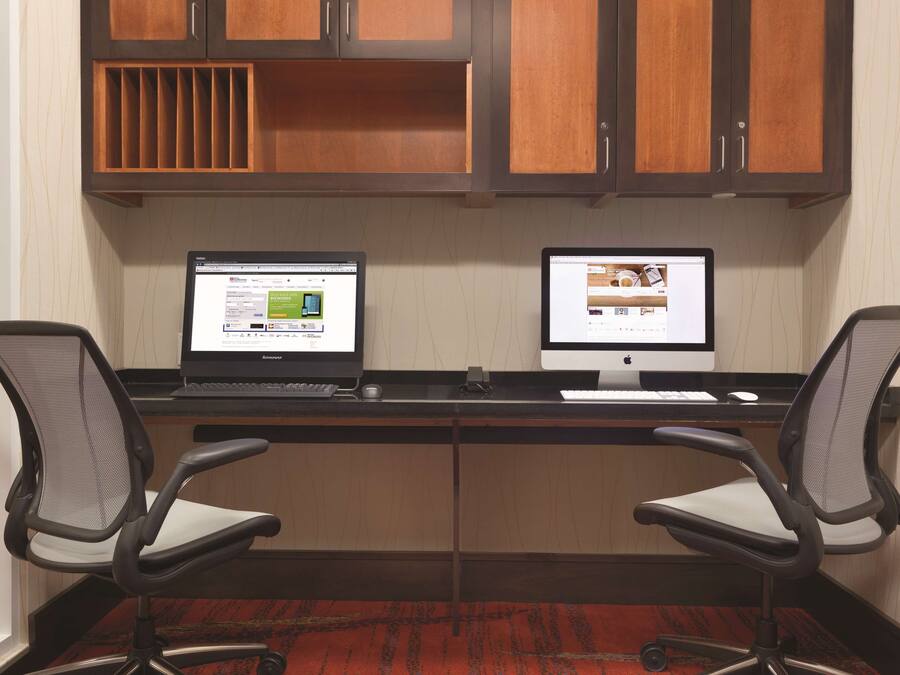 Un'area di lavoro con due computer, due sedie da ufficio e mobili contenitori in legno.