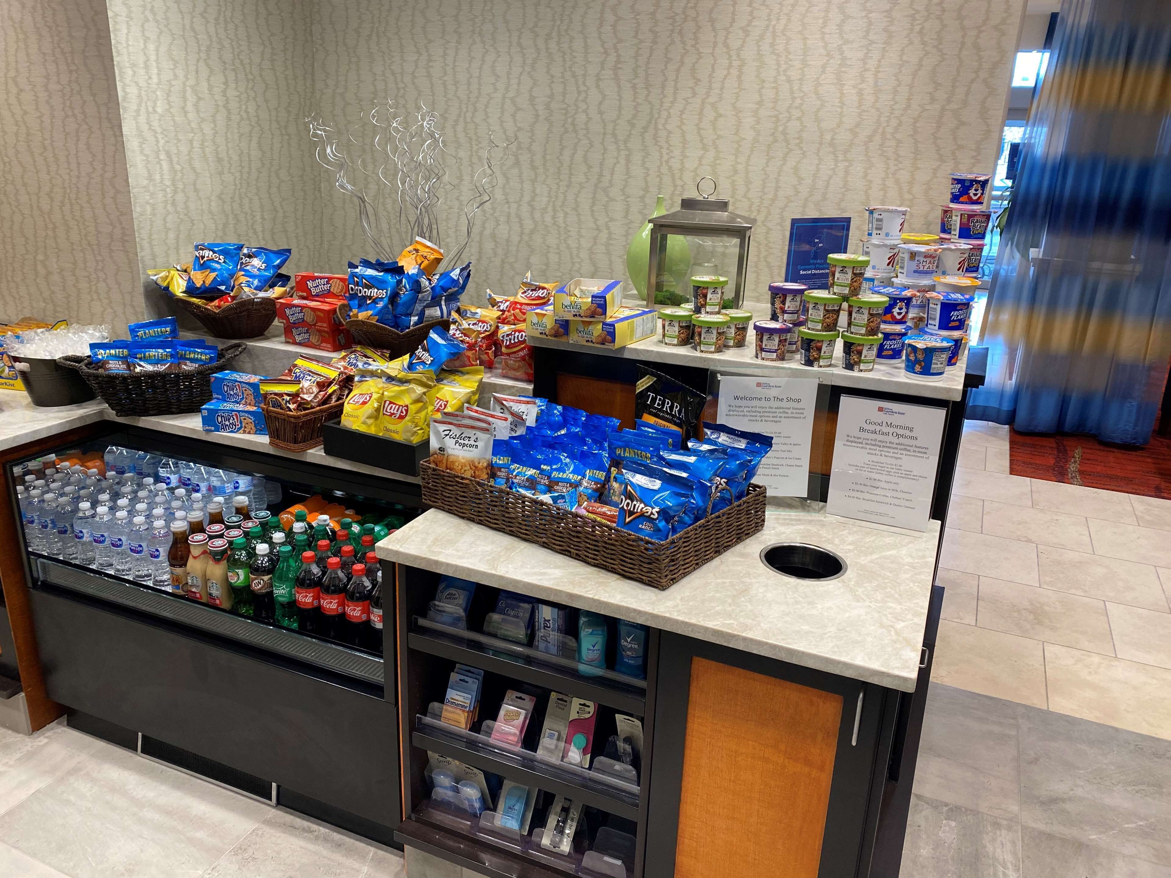 Eine Auswahl an Snacks und Getränken in der Hotelhalle, darunter Snacks, Wasserflaschen und Kaffee.