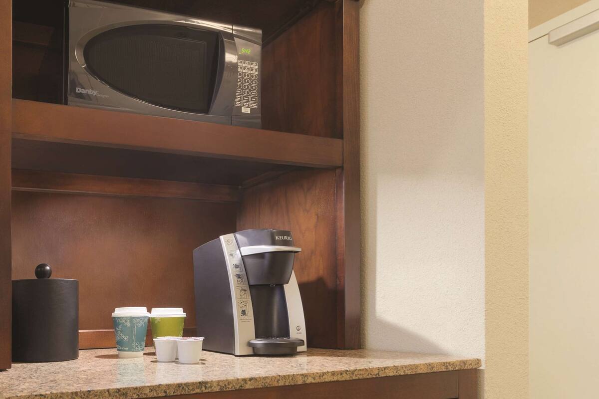 A kitchen with a microwave, coffee maker, and a refrigerator.